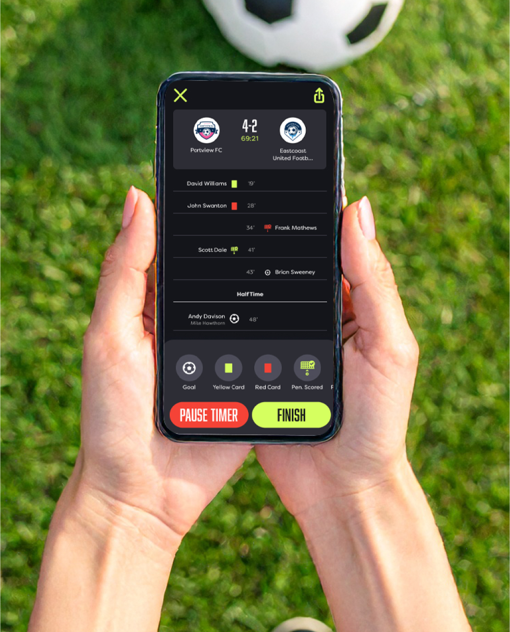 Hands holding phone on a soccer pitch